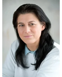 Porträt von Mag. Sabine Keller, einer Frau mit langen, dunklen Haaren und einem freundlichen Lächeln